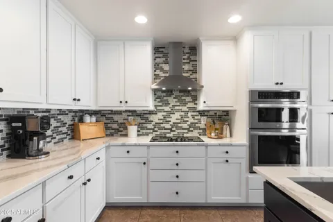 a kitchen with granite countertop white cabinets and stainless steel appliances