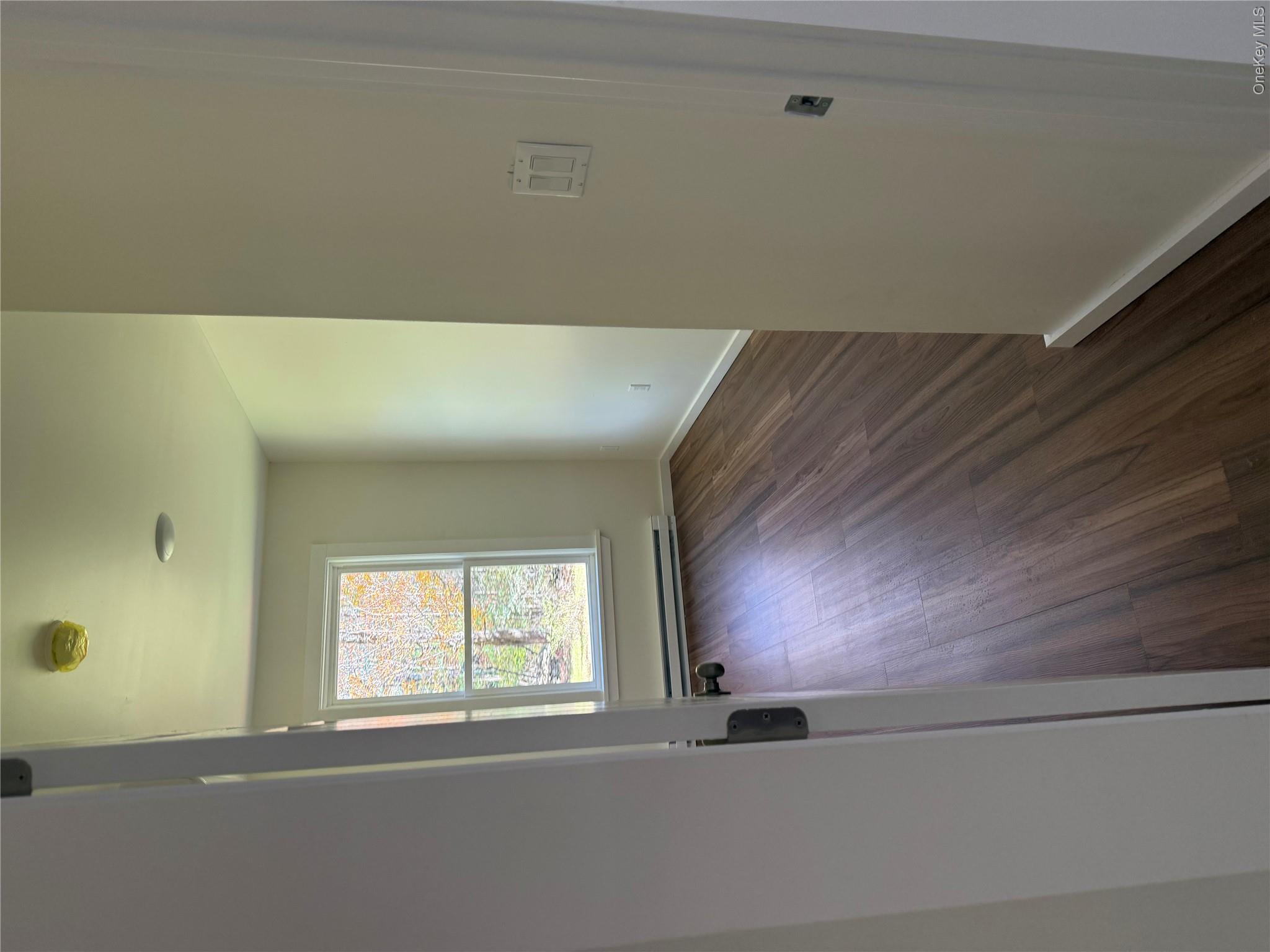 553 Cold Spring Road Monticello, NY 12701 - Photo 4 of 15 an empty room with wooden floor and windows