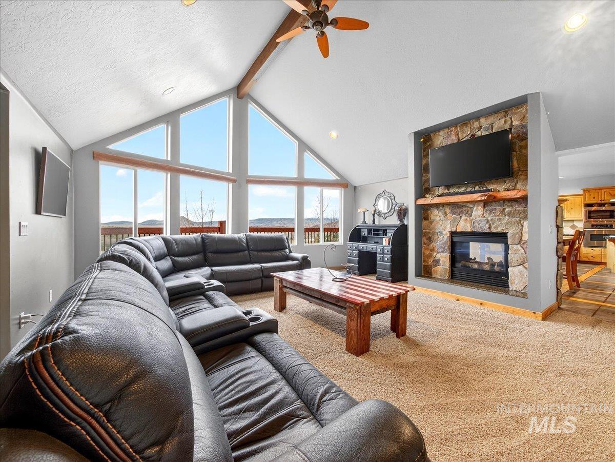 11714 Chukar Ridge Lane Horseshoe Bend, ID 83629 - Photo 12 of 50 Living room featuring beamed ceiling, a fireplace, ceiling fan, carpet floors, and a textured ceiling
