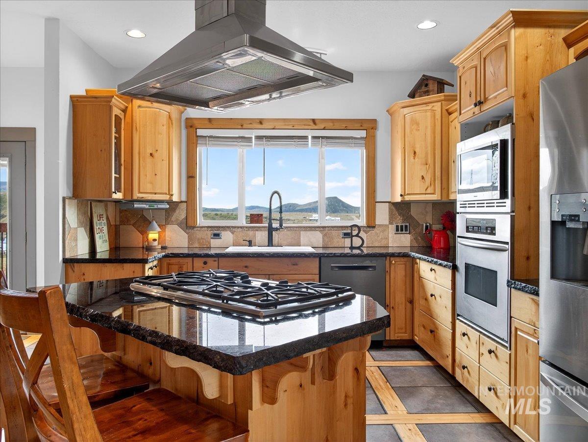 11714 Chukar Ridge Lane Horseshoe Bend, ID 83629 - Photo 20 of 50 Kitchen featuring island range hood, stainless steel appliances, inlaid floor details, recessed lighting, and light wood finish cabinets
