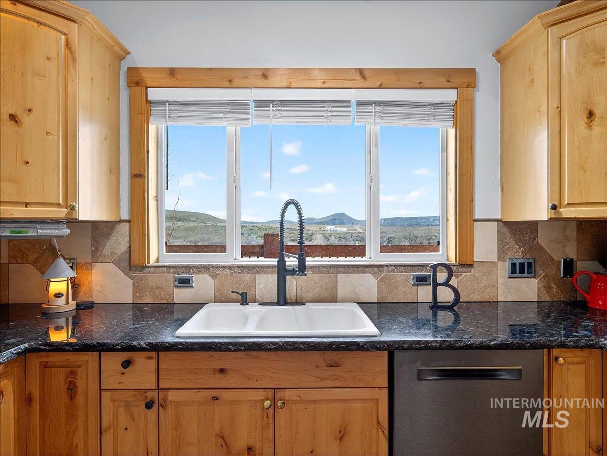 11714 Chukar Ridge Lane Horseshoe Bend, ID 83629 - Photo 21 of 50 Kitchen featuring light wood finish cabinets, dishwasher, tasteful backsplash, and dark stone counters
