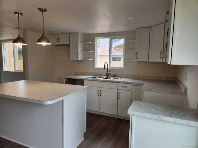 a kitchen that has a lot of cabinets in it and wooden floor