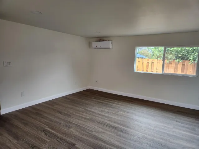 a view of an empty room with wooden floor and windows