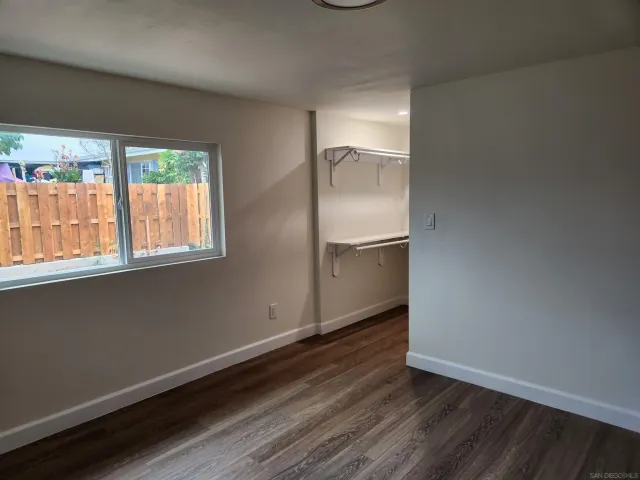 an empty room with wooden floor cabinet and windows