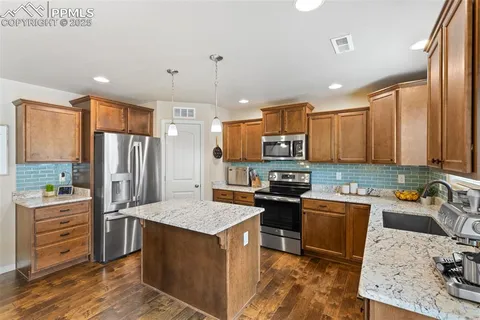 a kitchen with kitchen island granite countertop a sink counter top space appliances and cabinets
