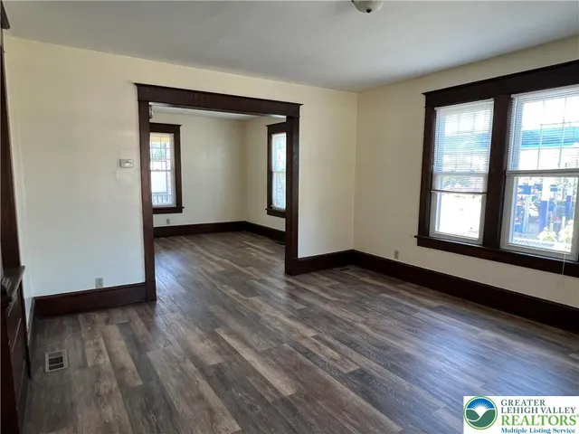 an empty room with wooden floor and windows
