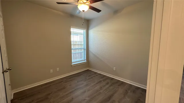 an empty room with chandelier fan and windows