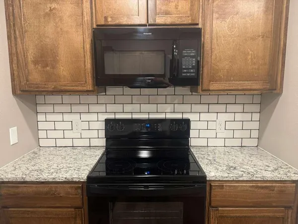 a kitchen with granite countertop a sink and a white wooden cabinets