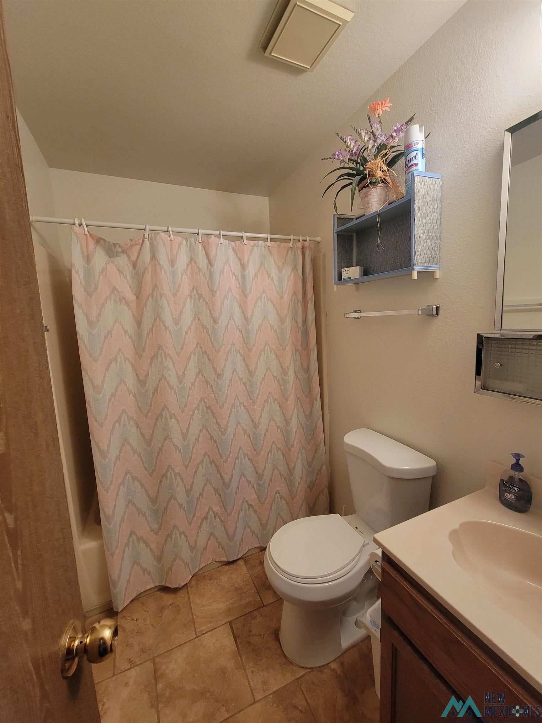 501 Springland Boulevard Elephant Butte, NM 87935 - Photo 14 of 38 Bathroom featuring a shower/tub combination, tile flooring, a white toilet, and a vanity with a light-colored countertop and dark wood cabinetry