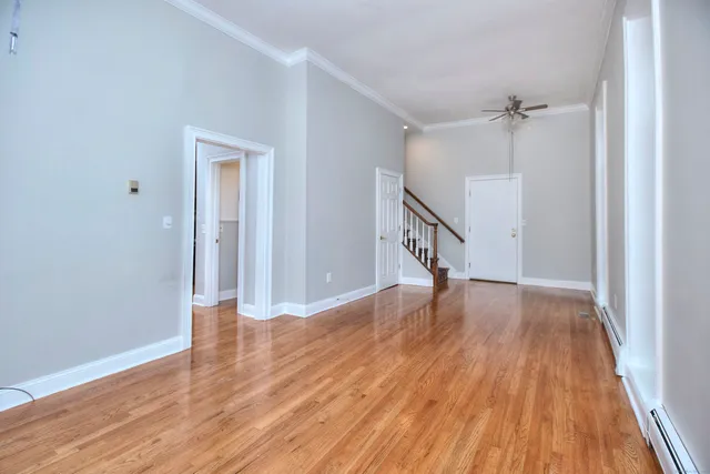 a view of empty room with wooden floor and fan