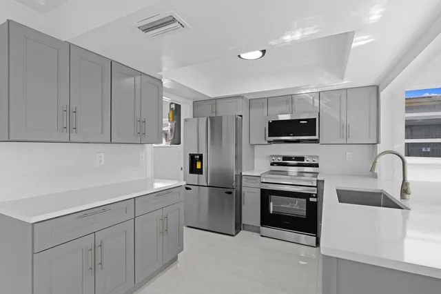 a kitchen with stainless steel appliances granite countertop a sink dishwasher stove top oven and refrigerator