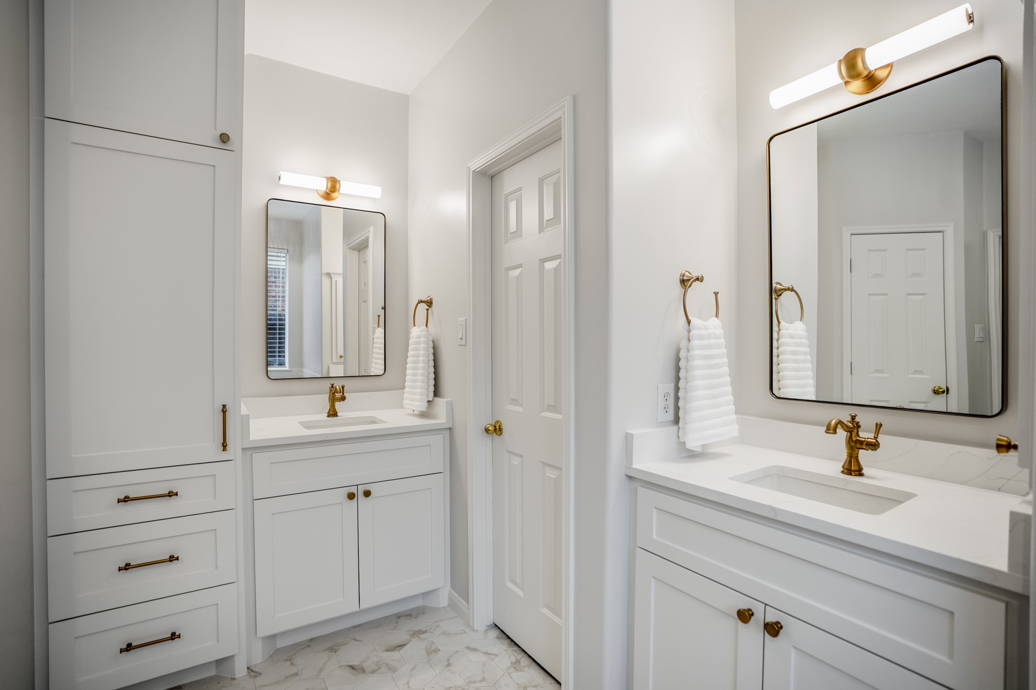 6311 Sparrows Glen Lane Spring, TX 77379 - Photo 20 of 50 A closer look at the primary bath shows the thoughtful storage built into the renovation, from separate vanity areas to the linen tower with drawers and cabinet space, all finished with warm brass accents and clean white cabinetry.