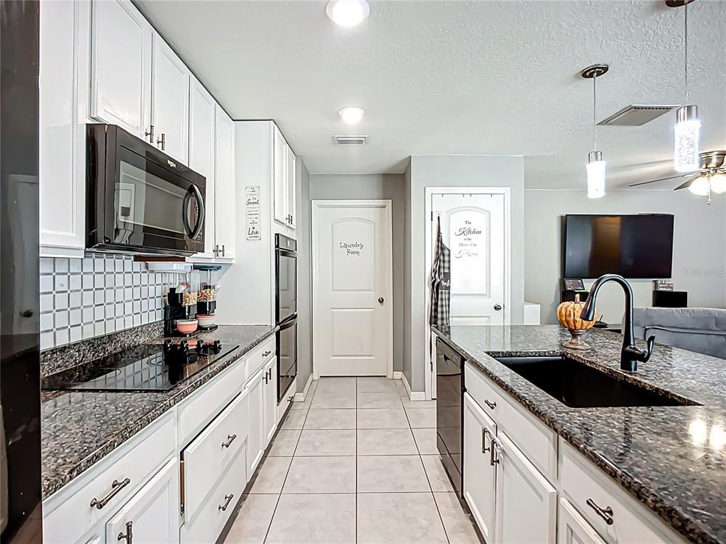 7707 Sunshine Bridge Avenue Gibsonton, FL 33534 - Photo 6 of 33 a large kitchen with granite countertop a sink and a stove top oven a granite counter space and cabinets