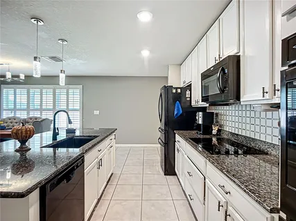 a kitchen with stainless steel appliances granite countertop a sink a stove top oven and a refrigerator