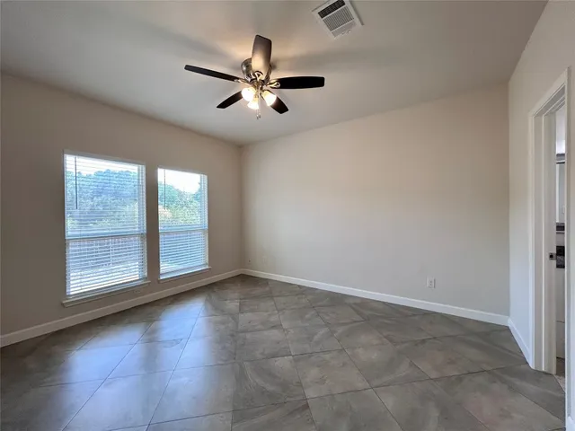 a view of an empty room with chandelier fan