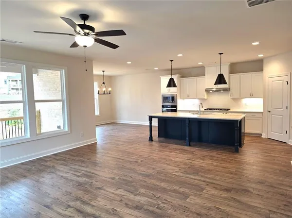 a view of kitchen with kitchen island stainless steel appliances wooden floor and window