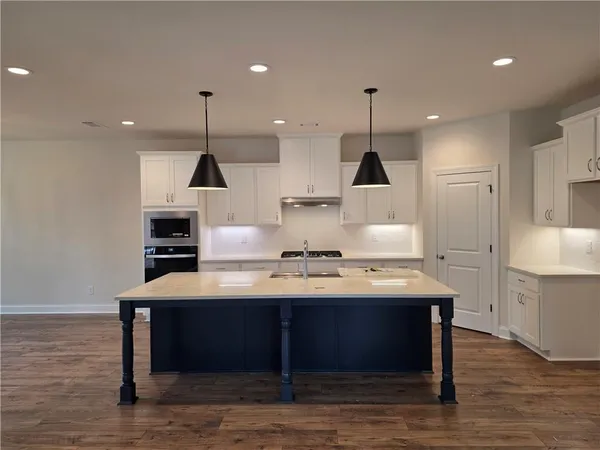 a view of a room with kitchen island stainless steel appliances a sink and wooden floor