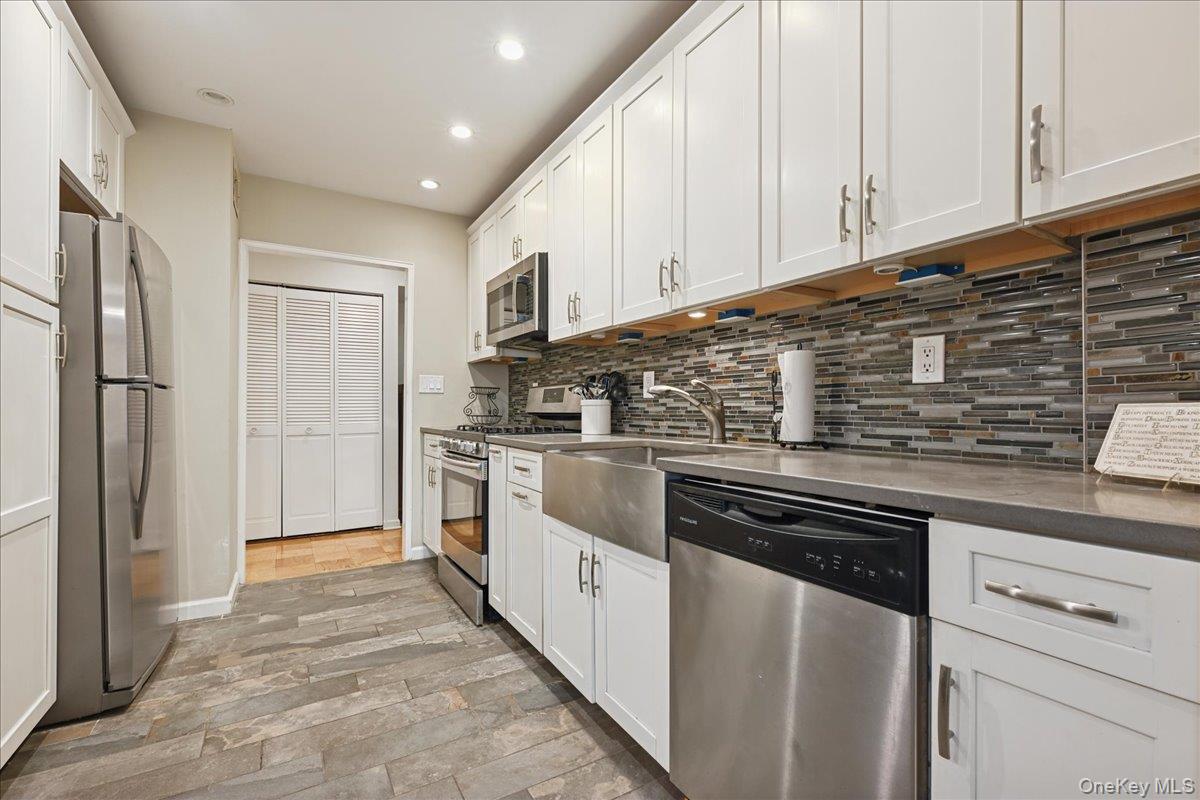 700 Shore Road, Unit 4O Long Beach, NY 11561 - Photo 10 of 42 a kitchen with white cabinets and stainless steel appliances