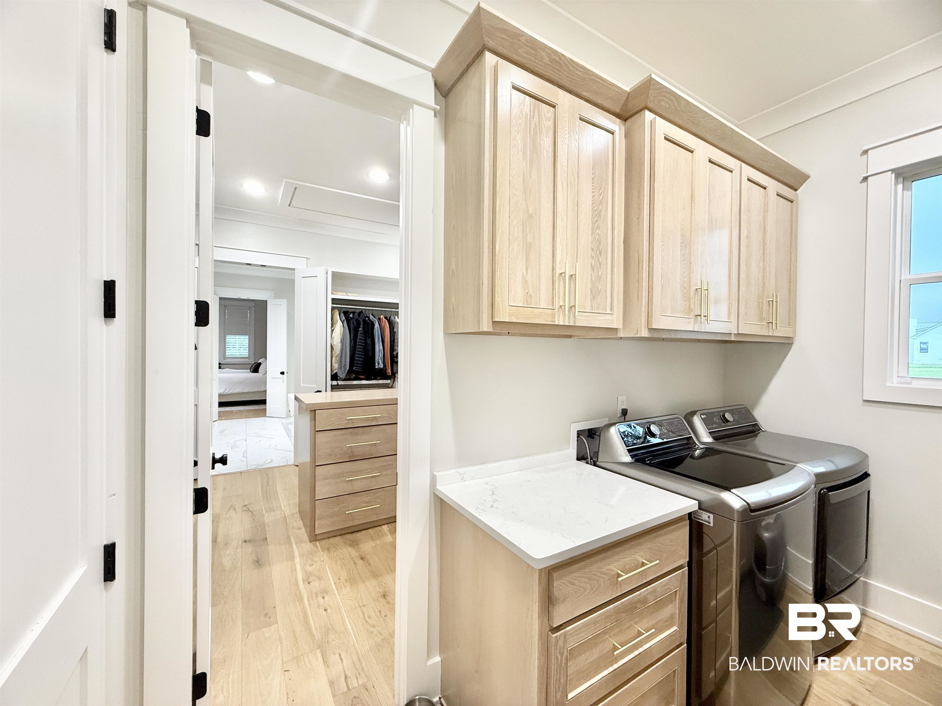21767 Gallery Boulevard Fairhope, AL 36532 - Photo 40 of 74 Laundry room featuring cabinet space, light wood-style flooring, ornamental molding, and washer and dryer