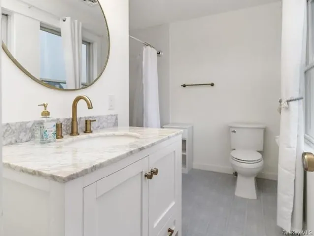 a bathroom with a granite countertop toilet sink and mirror