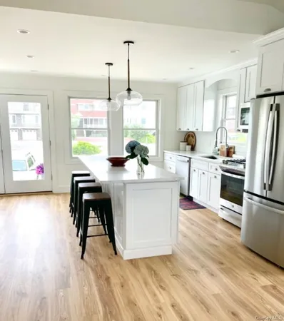 a kitchen with stainless steel appliances a dining table chairs stove refrigerator and cabinets