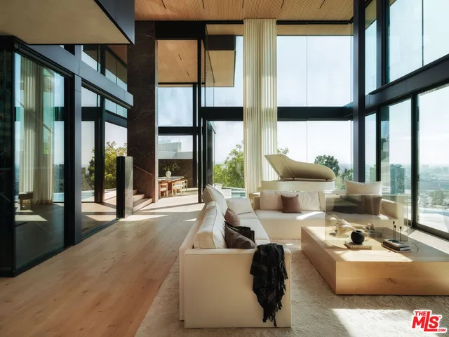 a living room with large windows a couch and chairs