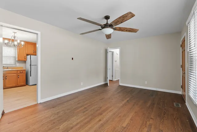 a kitchen with stainless steel appliances granite countertop a refrigerator a sink dishwasher a stove and white cabinets with wooden floor