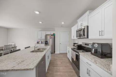 a kitchen with stainless steel appliances granite countertop a kitchen island a stove a table and chairs