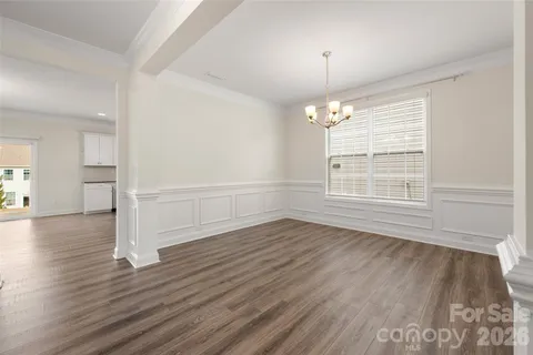 an empty room with wooden floor chandelier and windows