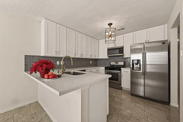 a kitchen with stainless steel appliances granite countertop a refrigerator a stove and a sink