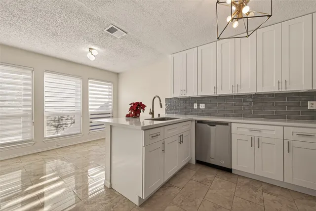 a kitchen with granite countertop white cabinets sink and window