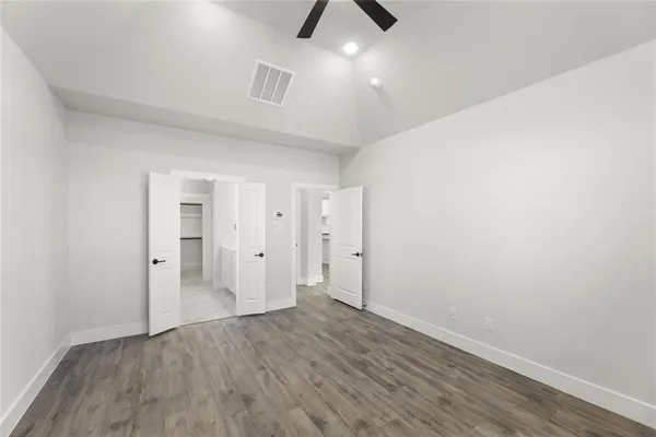 an empty room with wooden floor and ceiling fan
