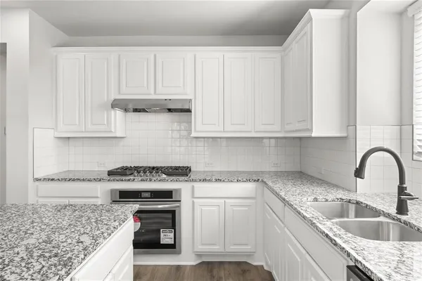 a kitchen with granite countertop a stove sink and cabinets
