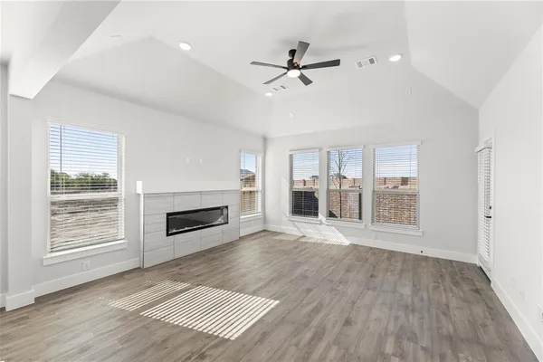 a view of an empty room with wooden floor fireplace and a window