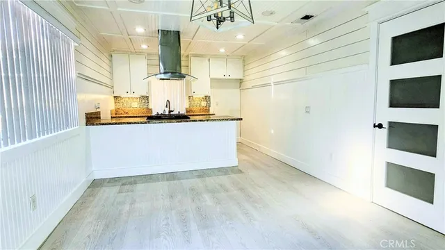 a large kitchen with stainless steel appliances a large counter top a stove and a wooden floors