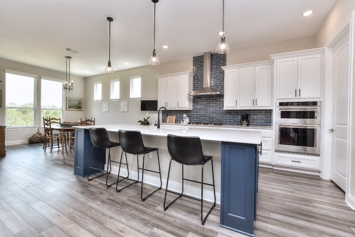 a kitchen with stainless steel appliances kitchen island granite countertop a table chairs and a sink