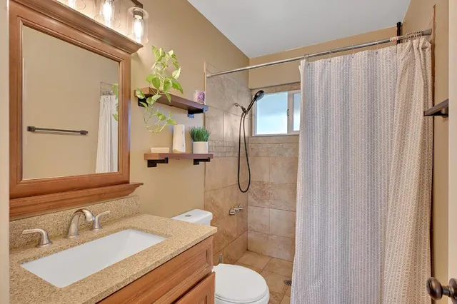 a bathroom with a granite countertop shower and a toilet
