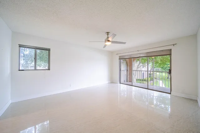 an empty room with a ceiling fan and window