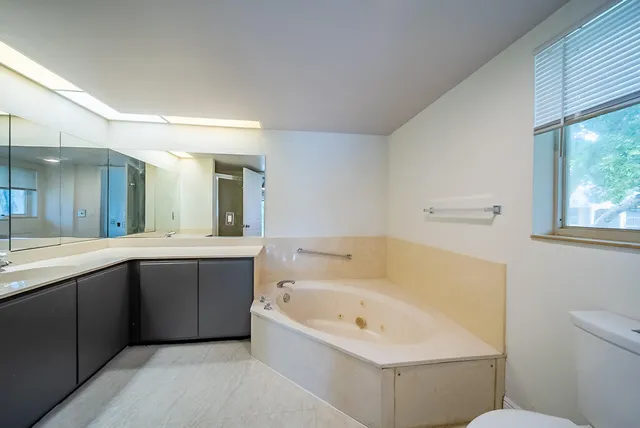 a bathroom with a bathtub a double vanity sink and mirror