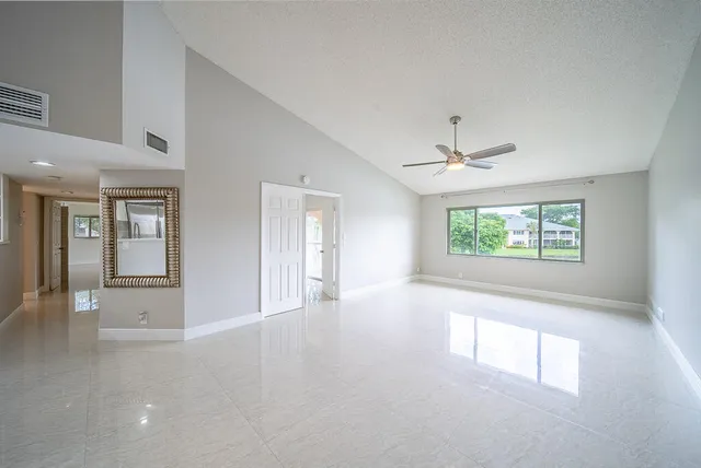 an empty room with windows and ceiling fan