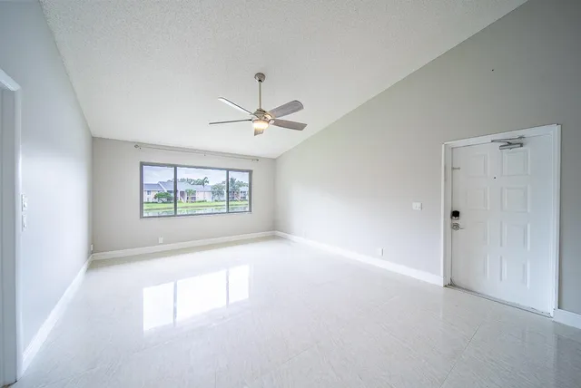 an empty room with windows and chandelier fan