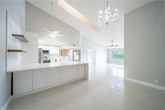 a large white kitchen with cabinets a sink and appliances