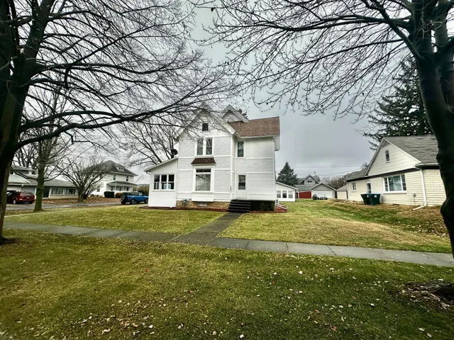 a big white house with a yard and trees