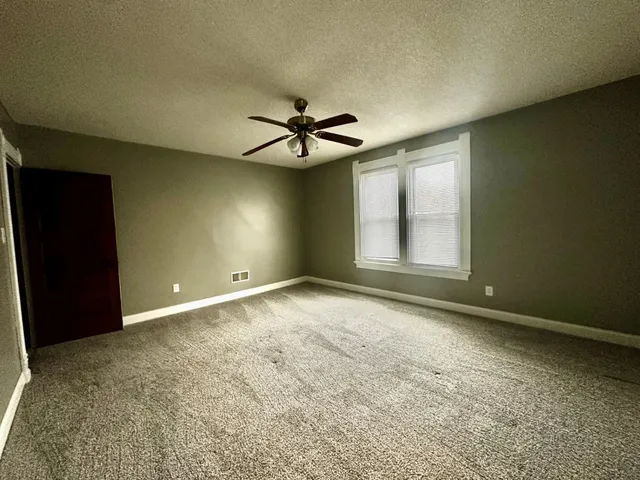 an empty room with windows and fan