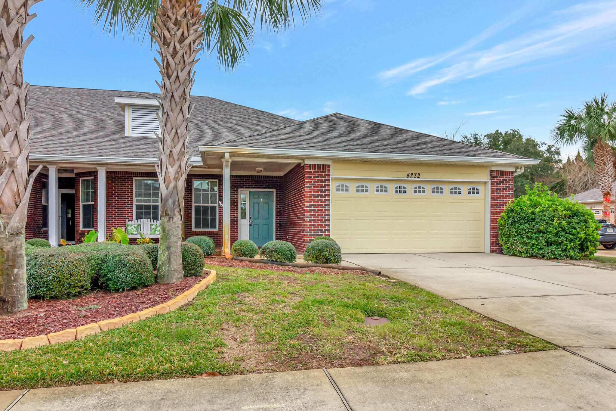 front view of a house with a yard and palm trees
