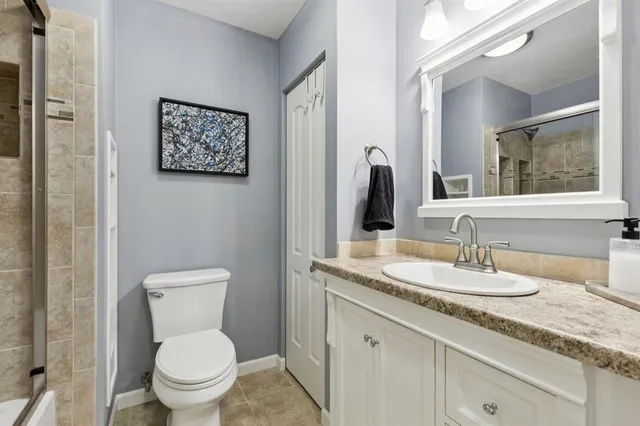 a bathroom with a granite countertop toilet sink and mirror