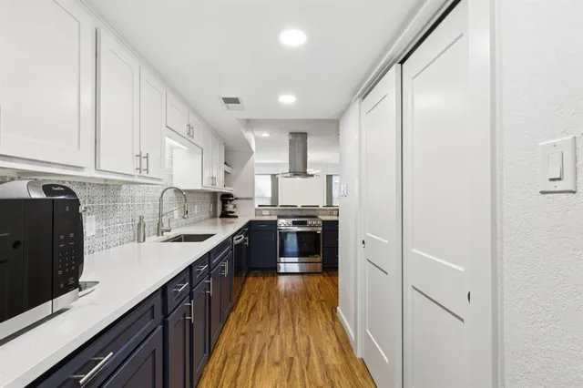 a kitchen with stainless steel appliances granite countertop a refrigerator a stove and a sink