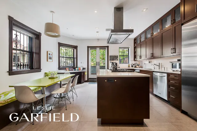 a kitchen with stainless steel appliances granite countertop a stove refrigerator a dining table and chairs with wooden floor