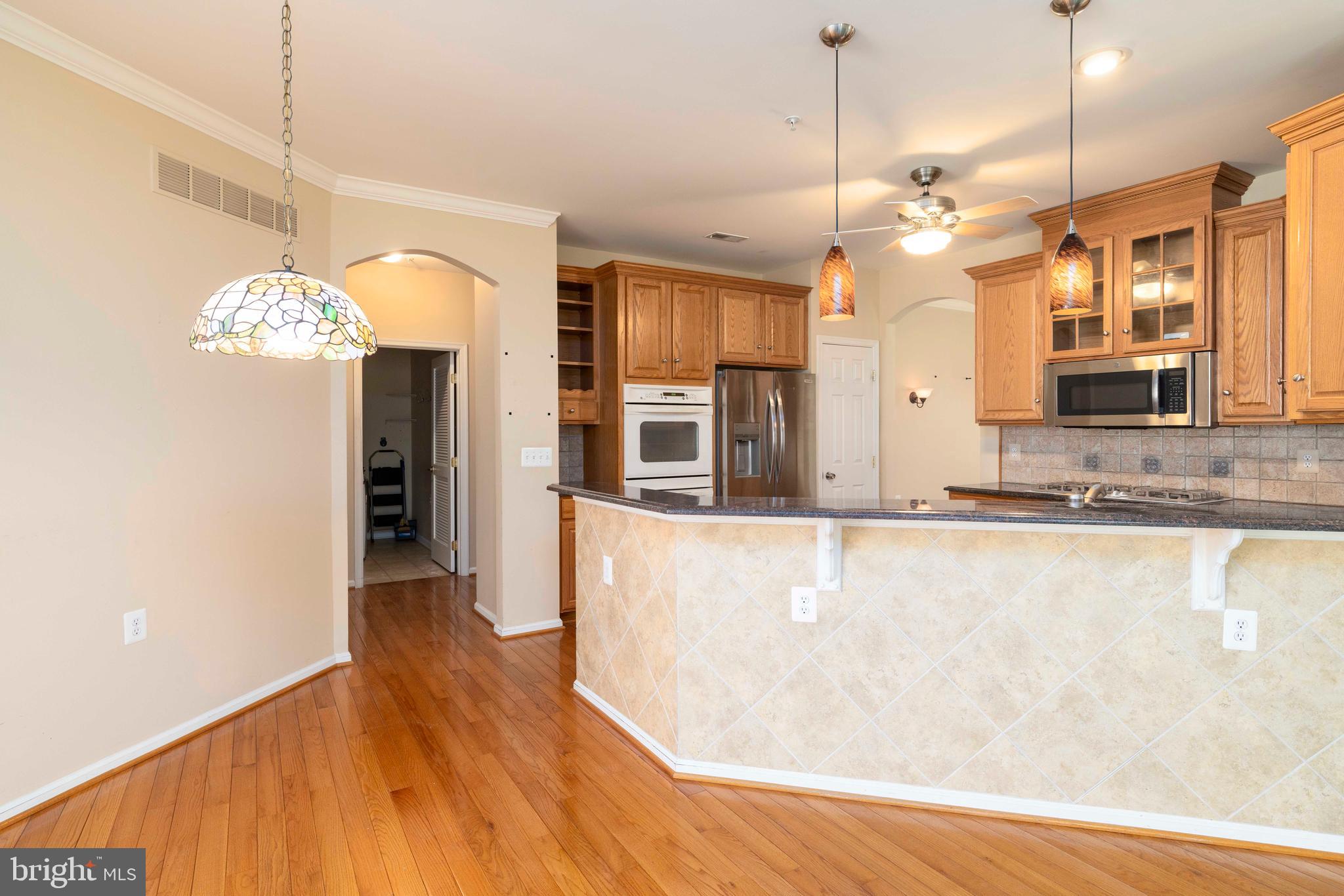1028 Conway Court Warminster, PA 18974 - Photo 13 of 32 a large kitchen with granite countertop a large counter top space wooden floor stainless steel appliances and a chandelier