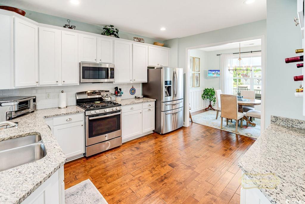 2110 Silver Spring Lane Myrtle Beach, SC 29577 - Photo 4 of 40 Kitchen with appliances with stainless steel finishes, white cabinets, backsplash, light wood-type flooring, and recessed lighting